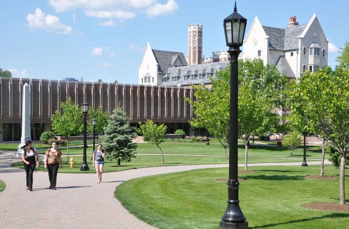 Students walk across campus with the Gannett-Tripp 图书馆 and Meier Hall in the background